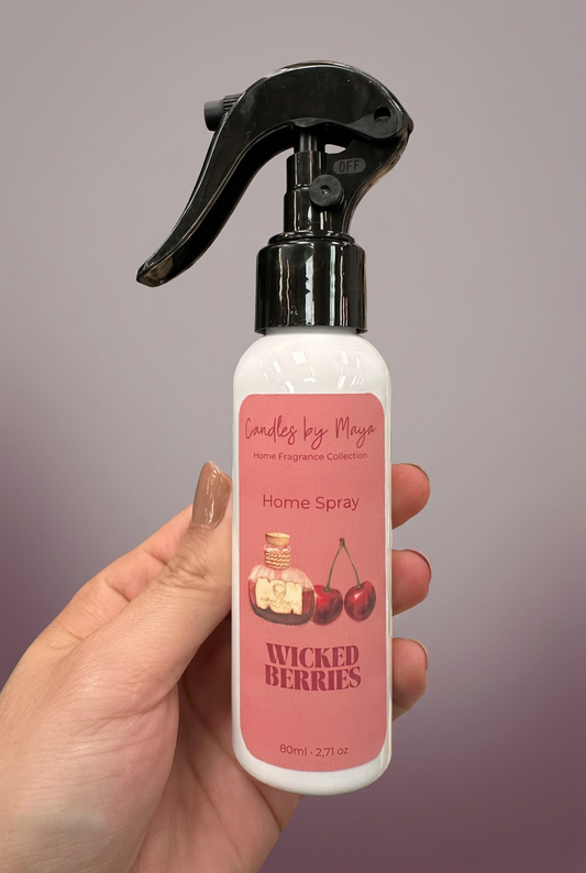 Wicked Berries Home Spray held in a hand against a soft muted mauve studio background