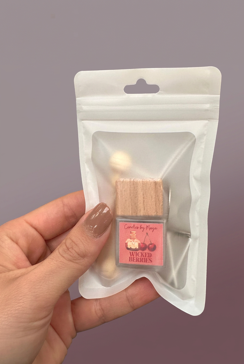 Wicked Berries car diffuser in its original pouch held in a hand against a soft mauve studio background